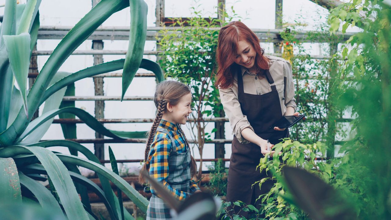 services-03 Mother and daughter enjoying gardening together in a lush greenhouse.