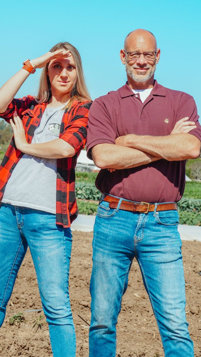 A man and woman standing confidently in a field, showcasing teamwork and agriculture.